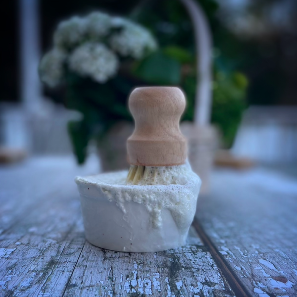 a ramekin with soap, bubbles and soap brush