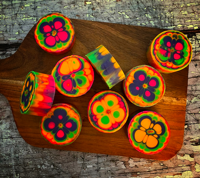 wooden cutting board with 9 colorful round soaps on it