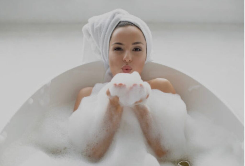 woman in bathtub blowing bubbles